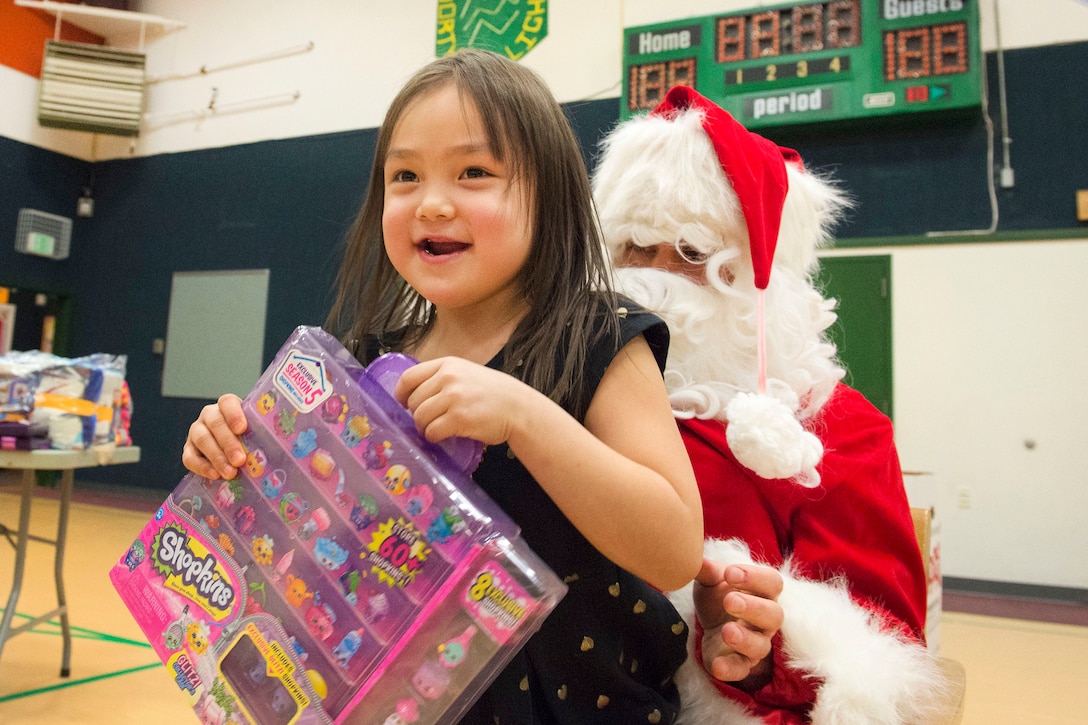 A young girl smiles after receiving a present from Santa Claus during Toys for Tots at Deering School in Deering, Alaska, Nov. 30, 2016. Santa was assisted by Marine Corps Capt. Michael Sickels, assigned to Detachment Delta, 4th Law Enforcement Battalion. Toys for Tots is supported by the United States Marine Corps Reserve with a goal of delivering, through a new toy, a message of hope to youngsters that will assist them in becoming responsible, productive and patriotic citizens. Two teams of Marines traveled via snow machine to 10 remote villages in the vicinities of Kotzebue to deliver toys to children during the holiday season. Air Force photo by Alejandro Pena