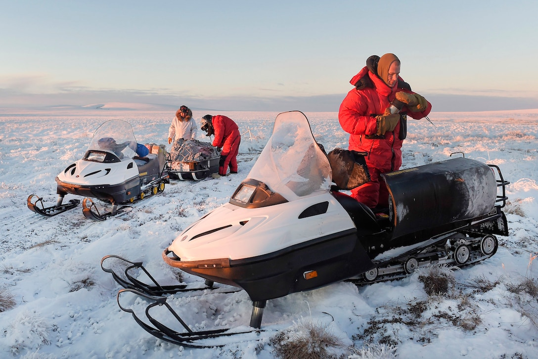 Marine Corps 1st Sgt. Joshua Guffey, right, Capt. Michael Sickels, center, and Dickie Moto, local guide, pause to momentarily rest and adjust their gear while traveling via snow machine from Deering to Kotzebue, Alaska, Dec. 1, 2016. Guffey and Sickels are assigned to Detachment Delta, 4th Law Enforcement Battalion. Air Force photo by Alejandro Pena