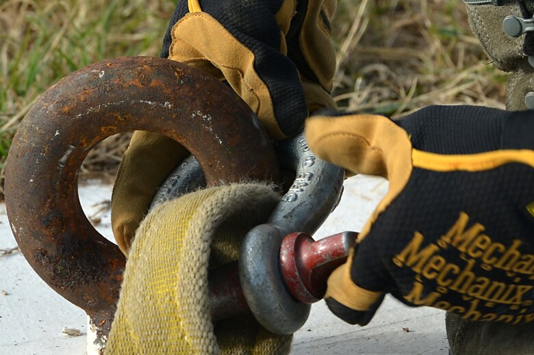 U.S. Air Force Senior Airman Garland Moore, 20th Civil Engineer Squadron power production technician, tightens a restraint onto the covering panel of a Barrier Artillery Kit-12 rotary friction brake aircraft arresting system at Shaw Air Force Base, S.C., Dec. 3, 2016. The restraints are used to hoist the covering during the installation process, allowing access to the rotary friction brake. (U.S. Air Force photo by Airman 1st Class Christopher Maldonado)