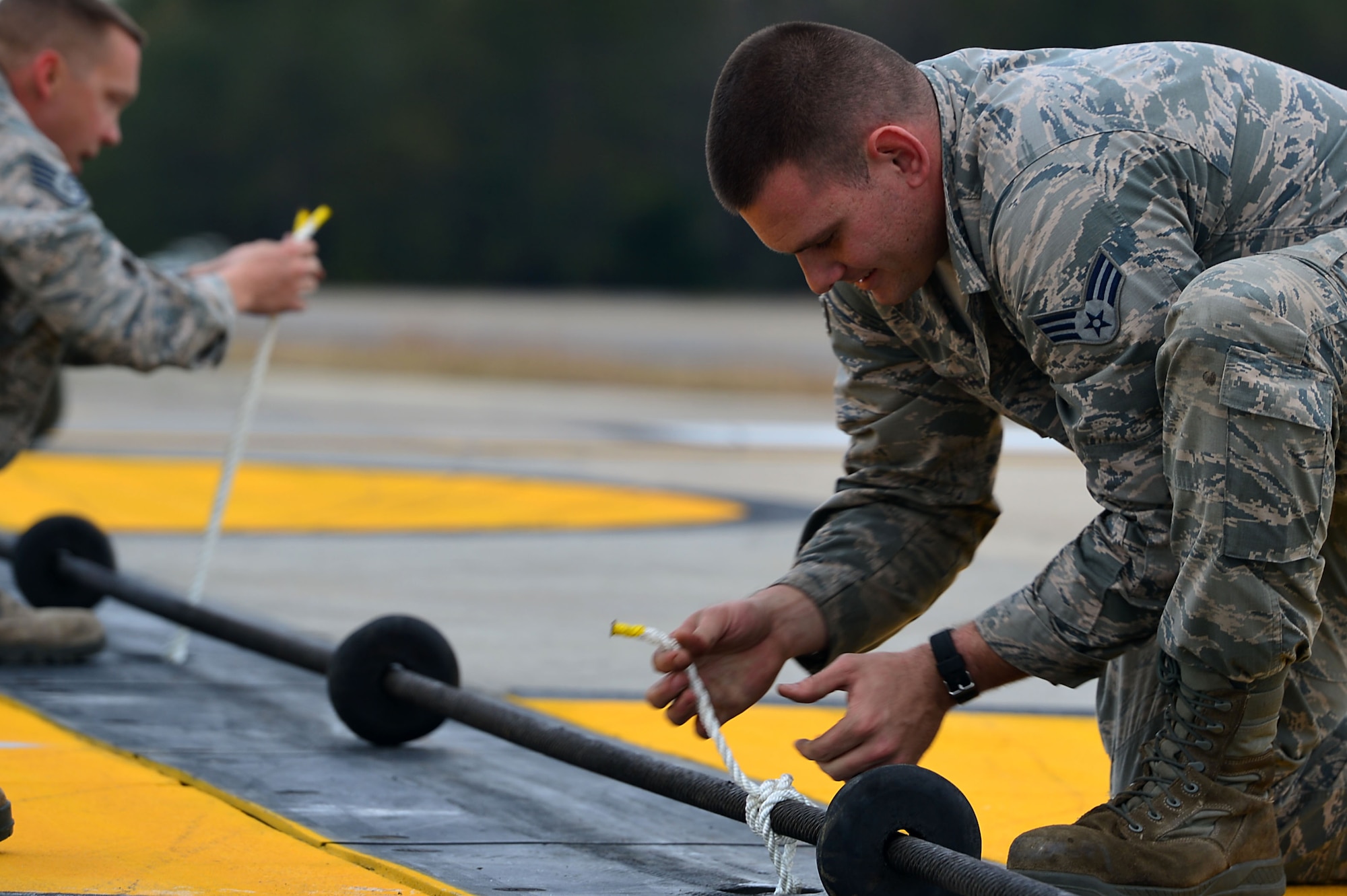 U.S. Air Force Senior Airman Jacob Smith, 20th Civil Engineer Squadron power production technician, prepares rubber donuts for a Barrier Artillery Kit-12 rotary friction brake aircraft arresting system cable at Shaw Air Force Base, S.C., Dec. 3, 2016. The rubber donuts elevate the cable to the proper height, providing proper distance for an aircraft to latch onto the cable in the event of an emergency landing. (U.S. Air Force photo by Airman 1st Class Christopher Maldonado) 
