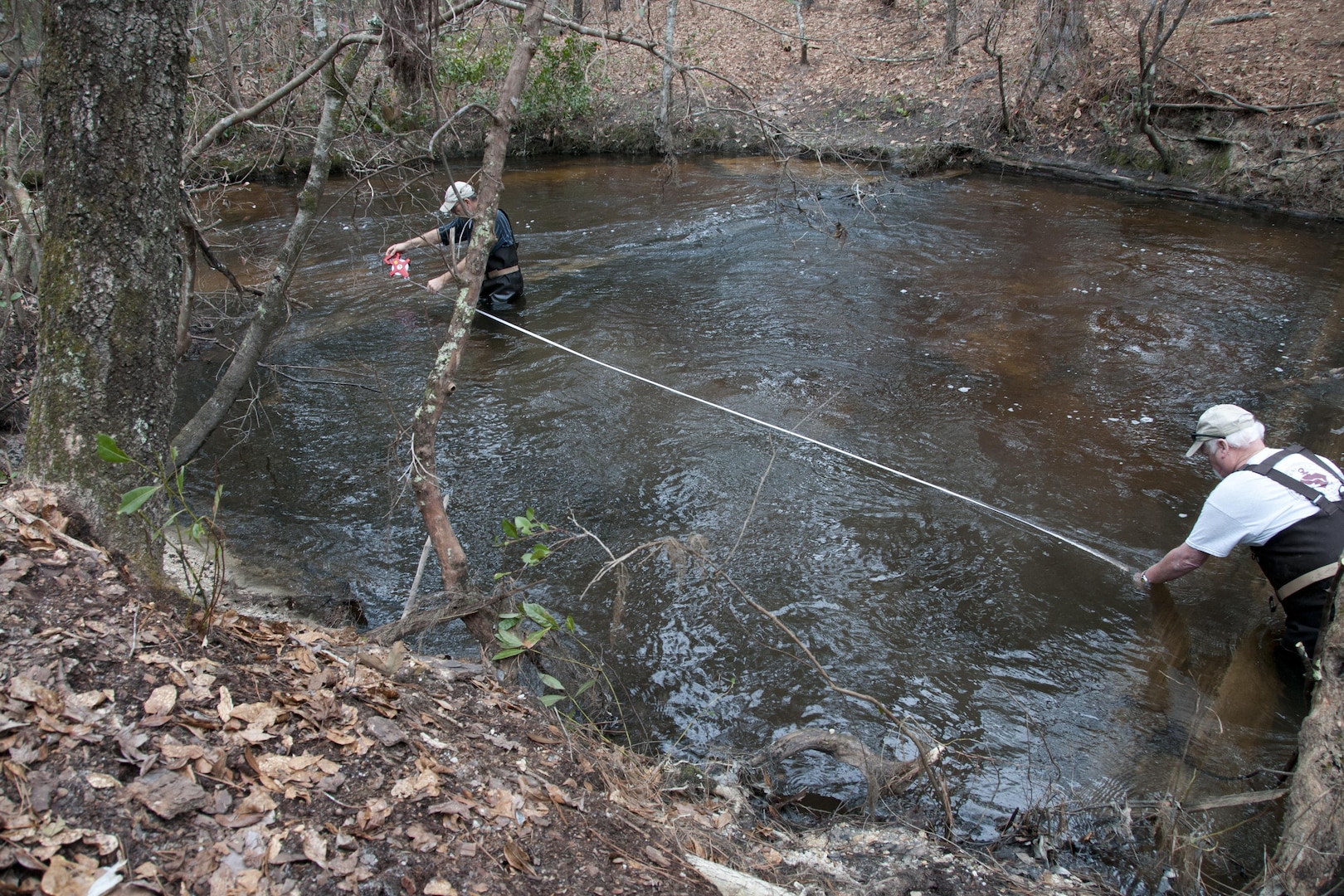 South Carolina Army National Guard hosts a team of archaeologists and conservation managers as they work at McCrady Training Center, Eastover, S.C., Feb. 2, 2016. After the historic flood of October 2015, drastic erosion exposed old transportation systems and disrupted construction timbers in a hollow core dam.  James Spirek and Joe Beatty, state underwater archaeologists measure distances between logs that built the dam. 