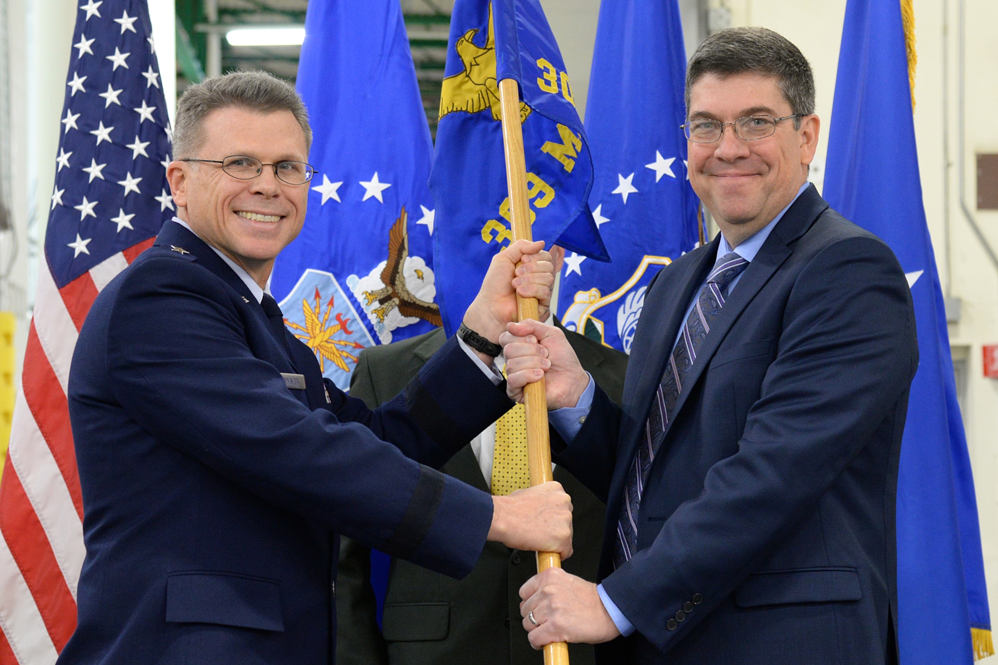Brig. Gen. Steven J. Bleymaier (left), Ogden Air Logistics Complex commander, passes the 309th Maintenance Support Group guidon to incoming director Jeff Wandrey during a change of leadership ceremony held Dec. 5 at Hill Air Force Base, Utah. (U.S. Air Force Photo by Alex R. Lloyd)