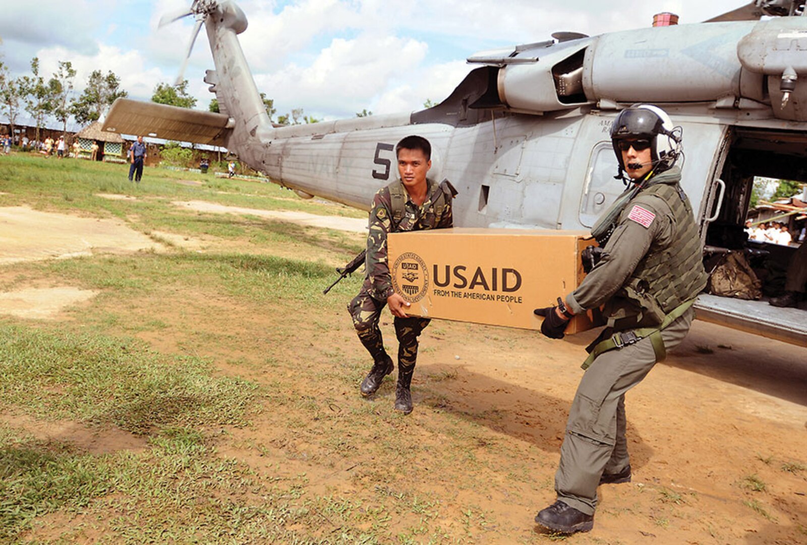 A U.S. Navy sailor and an Armed Forces Philippines soldier unload a box of humanitarian aid from USAID on Panay Island, demonstrating interagency and international cooperation.