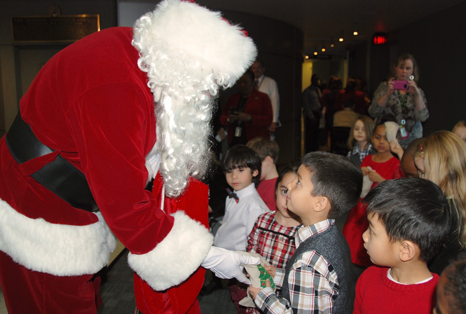 Pre-kindergarteners from the McNamara Headquarters Complex Child Development Center look at Santa Claus in awe while parents capture the moment taking cell-phone pictures. 