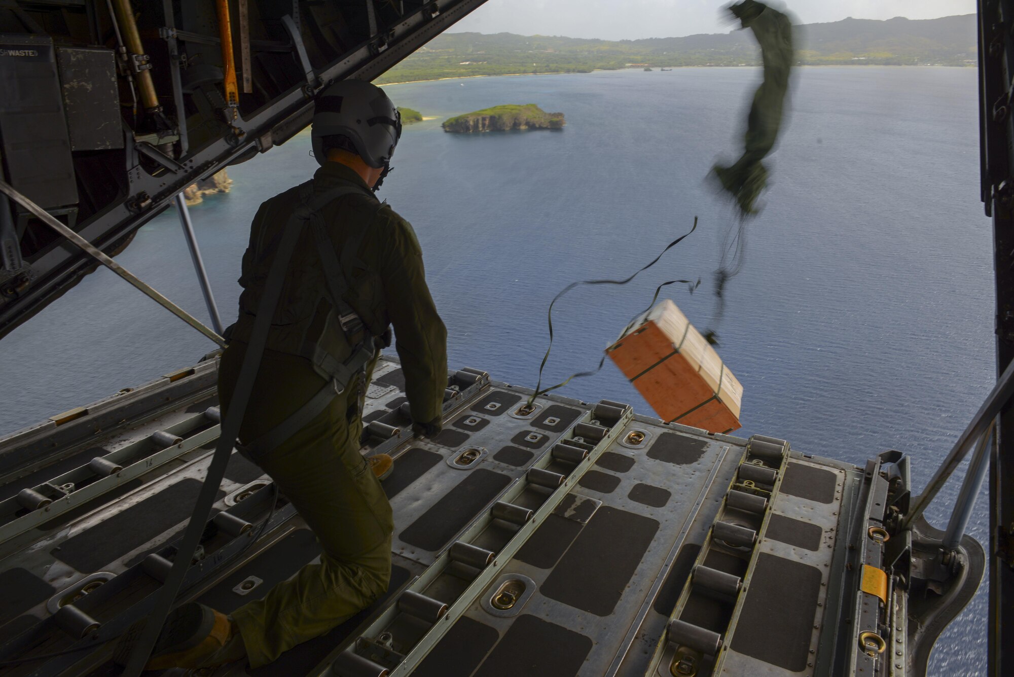 Senior Airman Anthony Schoof, 36th Airlift Squadron loadmaster, releases a bundle from the back of a C-130 H over the Micronesian Islands Dec. 5, 2016. The drop was part of Operation Christmas Drop, a joint-training operation between the U.S. Air Force, the Royal Australian Air Force, and the Japanese Air Self Defense Force which delivers bundles of donated supplies to the Micronesian Islands. This year is the 65th anniversary of OCD, making it the longest running humanitarian mission in the world. (U.S. Air Force photo by Senior Airman Elizabeth Baker/Released)