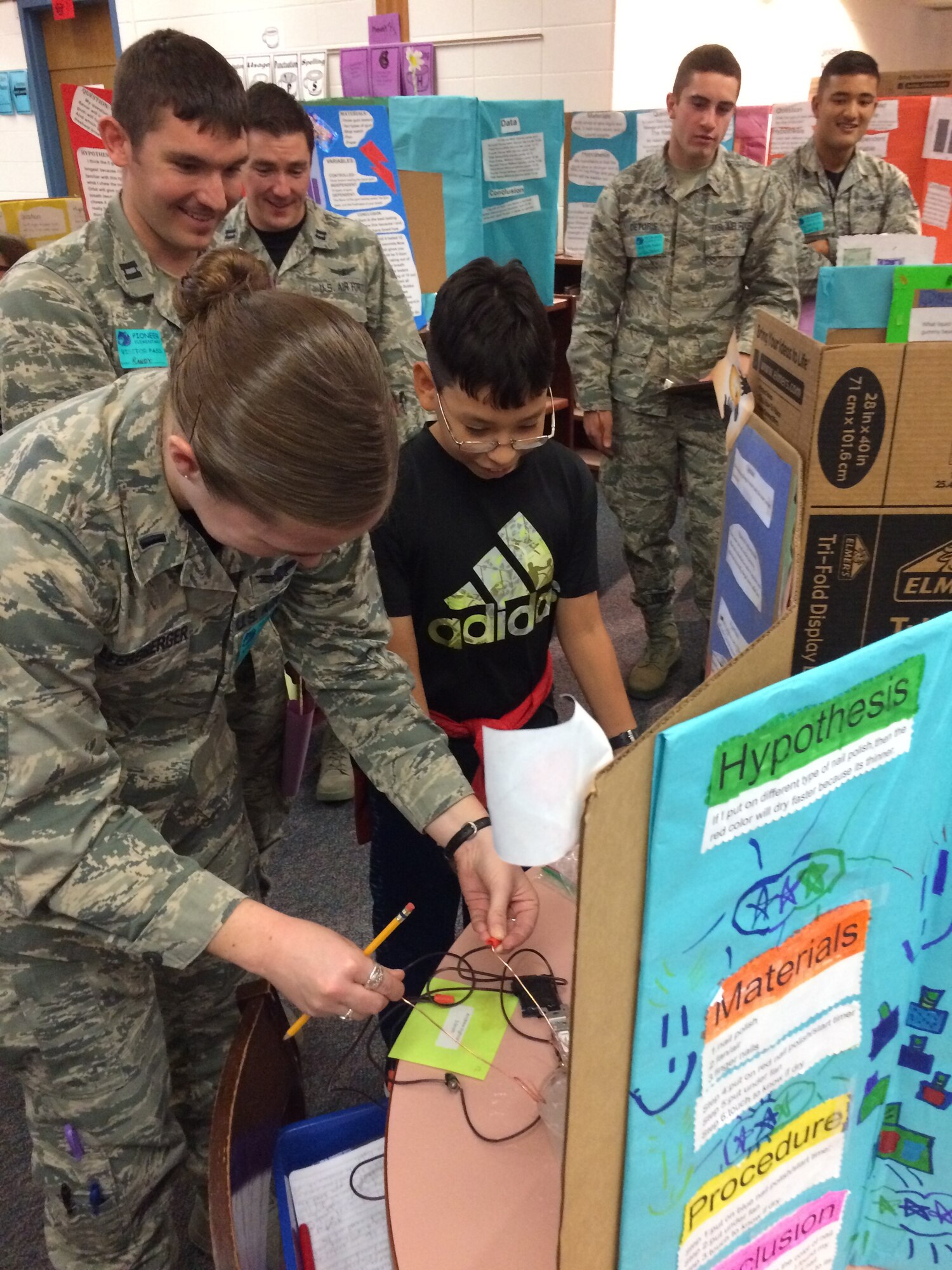 1st Lt. Margot Wolfersberger, 4th Space Control Squadron, tests a fifth grade student’s project by sending electrical currents through a salt water medium during a science fair at Pioneer Elementary School, Colorado Springs, Colo., Nov. 18, 2016.  Wolfersberger was one of 15 members from 4th SPCS who served as judges at the elementary school’s science fair. (Courtesy photo by 2nd Lt. Chris Jang)