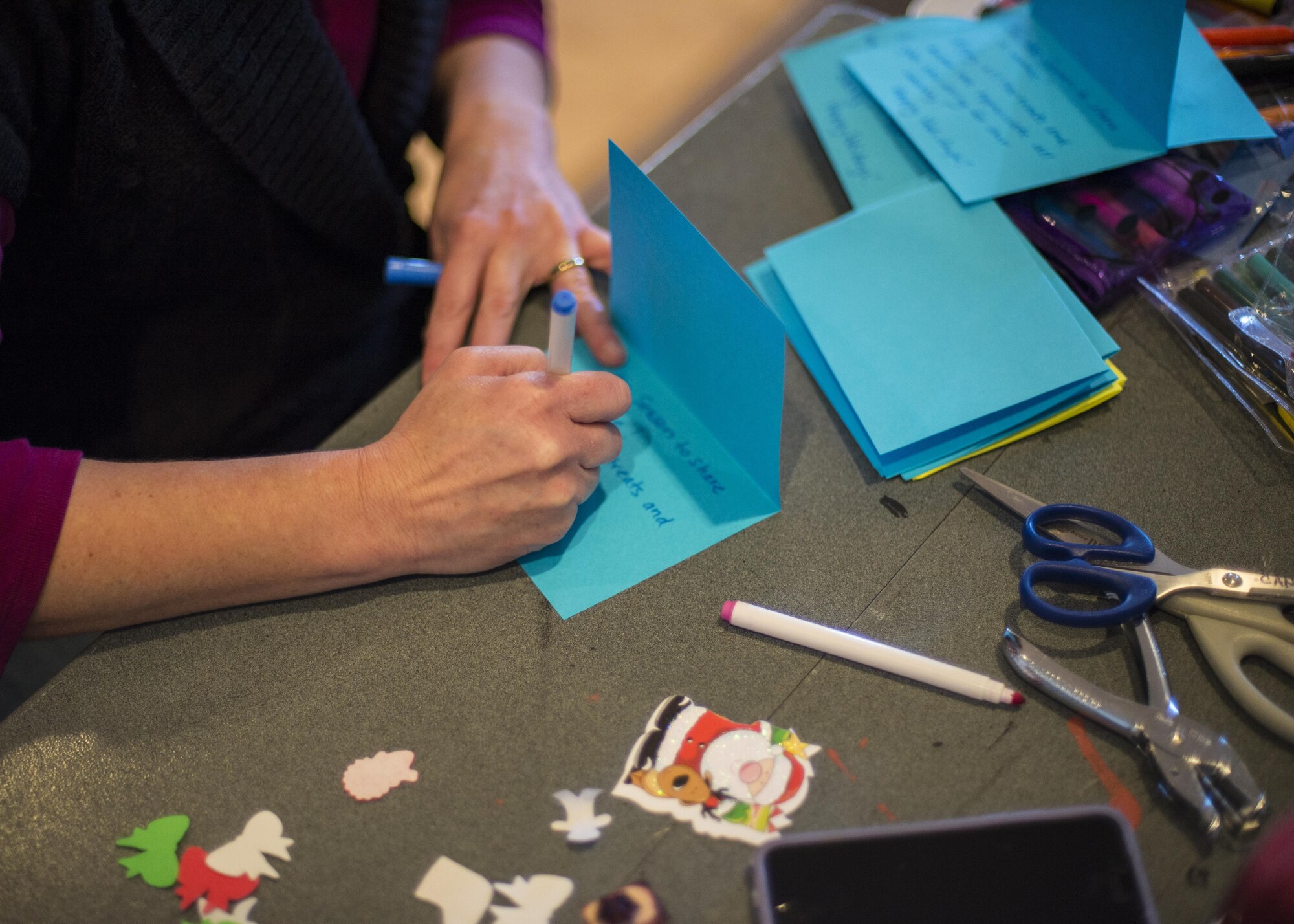 A volunteer crafts a handmade card, to adorn a package of cookies, for Holloman’s annual Airman Cookie Drive at the Community Activity Center at Holloman Air Force Base, N.M. on Dec 5, 2016. Cookie drive volunteers collected cookies from donors, organized cookies according to type, dispersed cookies into individual paper bags, and attached handmade cards to each bag of cookies. (U.S. Air Force photo by Airman 1st Class Alexis P. Docherty) 