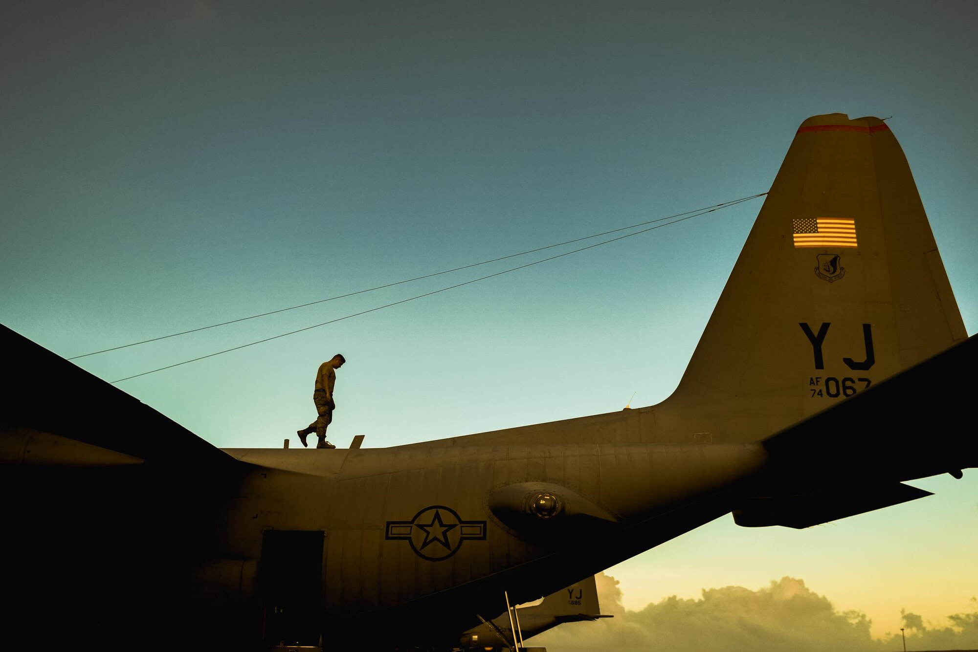 An Airman from the 374th Maintenance Squadron checks a C-130 Hercules for potential damage during Operation Christmas Drop 2016 at Andersen Air Force Base, Guam, Dec. 6, 2016. This year marks the 65th year of Operation Christmas Drop, which began in 1952, making it the world's longest-running airdrop mission. (U.S. Air Force photo by Senior Airman Delano Scott/Released)
