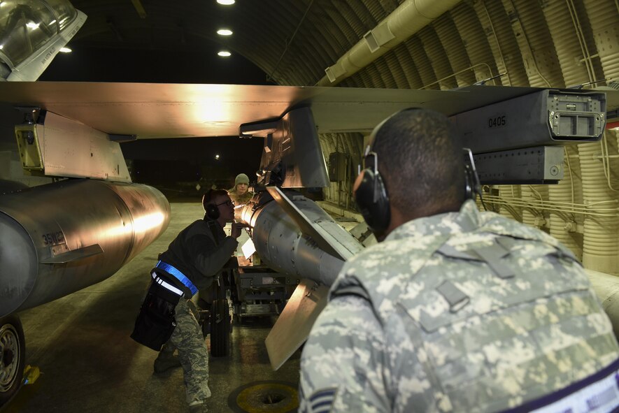 Staff Sgt. Kenneth Gullette, Airman 1st Class Gary Butlaff, and Senior Airman Braylyn Edwards, 35th Aircraft Maintenance Unit weapons load crew members, guide a GBU-31 bomb onto the wing of an F-16 Fighting Falcon using a MJ-1 Jammer bomb lift truck at Kunsan Air Base, Republic of Korea, Nov. 30, 2016. Members of the 35th AMU are responsible for safely loading, unloading, and properly positioning munitions onto F-16s. (U.S. Air Force photo by Senior Airman Michael Hunsaker/Released)