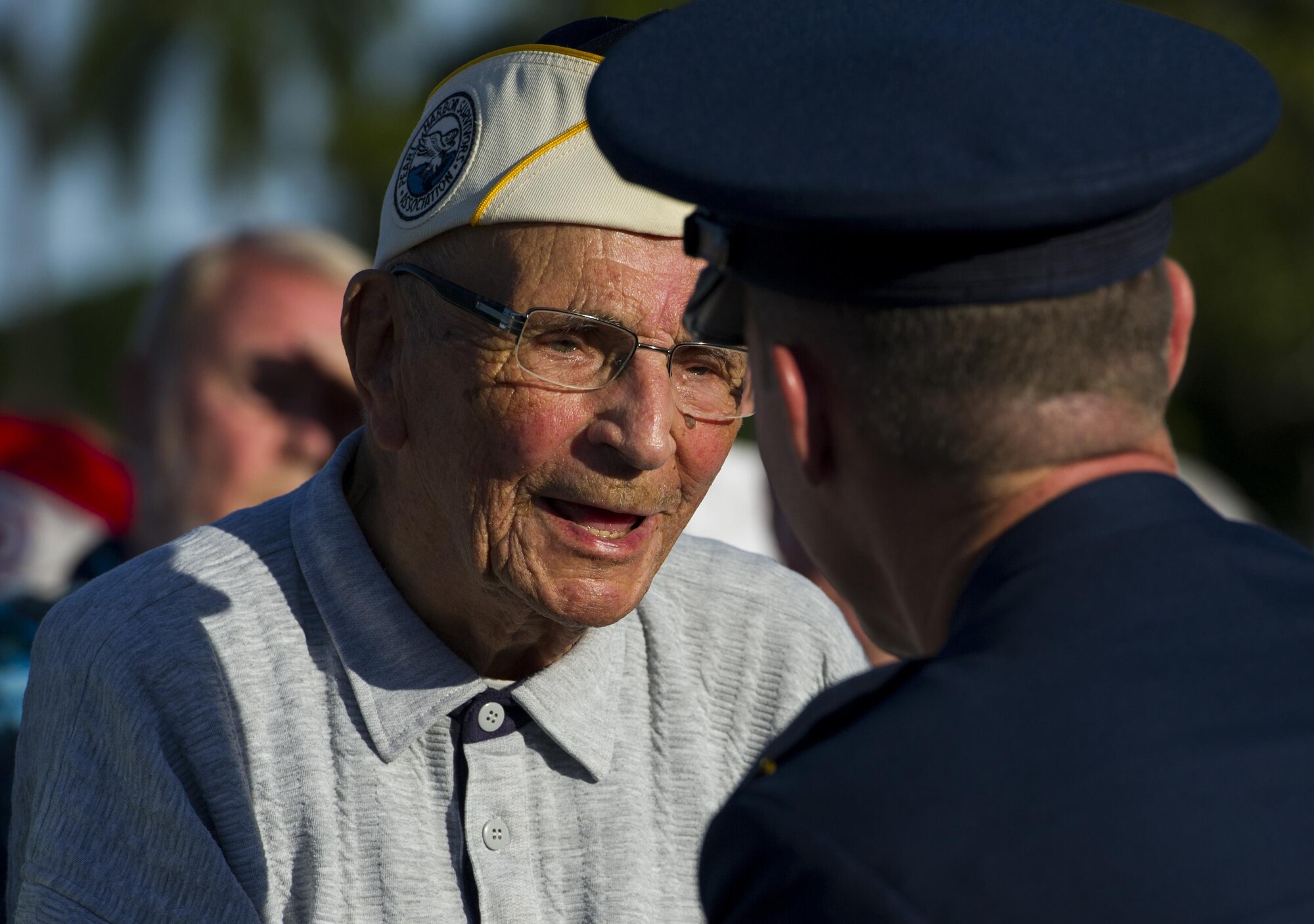 U.S. Army Private First Class Clifford McFarland, a survivor of the Hickam Field attack, converses with Col. Kevin Gordon, 15th Wing commander, while being given a gift during the 75th Commemoration of the Dec. 7, 1941 Attack on Hickam Field ceremony Dec. 7, 2016, at Joint Base Pearl Harbor-Hickam, Hawaii. On Dec. 7, 1941, McFarland witnessed a Japanese aircraft maneuver around the church steeple, shoot at the barracks, and take out the B-17 Flying Fortress and B-18 Bolo aircraft on the flightline. He spent the remainder of the day transporting water to a machine gun being used to repel the attackers. (U.S. Air Force photo by Tech. Sgt. Nathan Allen)