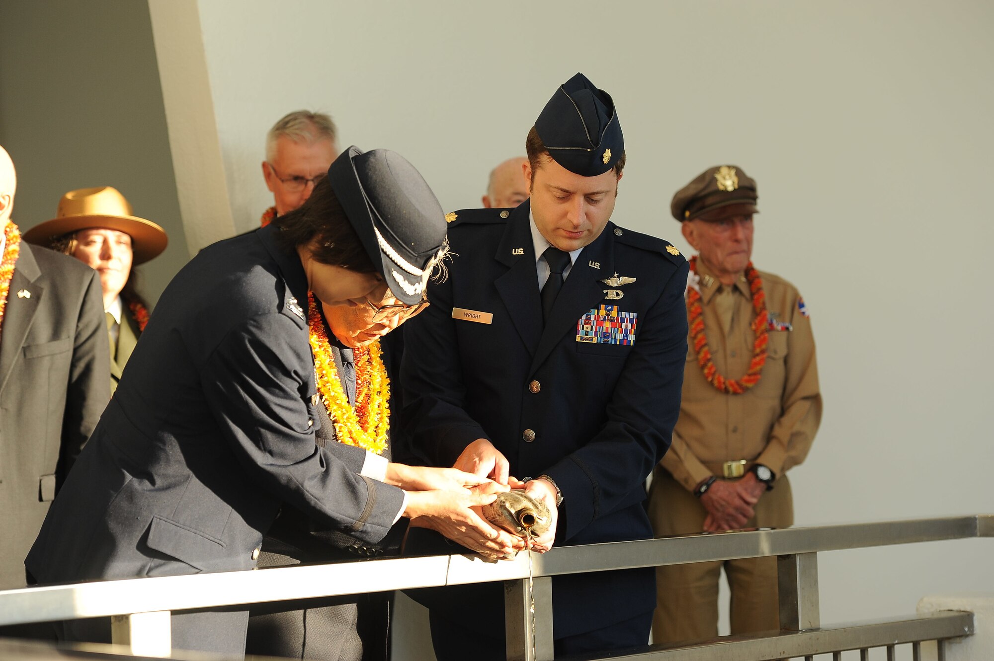 U.S. and Japanese Airmen join Dr. Hiroya Sugano in pouring bourbon whiskey over the USS Arizona Memorial at Joint Base Pearl Harbor-Hickam, Hawaii, Dec. 6, 2016, from a blackened canteen that flew aboard a B-29 Superfortress that crashed in Japan during WWII. Every year, Sugano brings the canteen from Japan to perform this highly respectful reconciliatory gesture towards those lost 75 years ago during the attacks on Pearl Harbor and Oahu. (U.S. Air Force photo by Senior Airman Bryan Andrews)