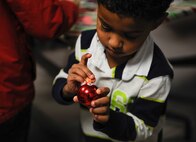 Khalil Mackey, son of Tech. Sgt. Corey Mackey, 786th Force Support Squadron glues an orange nose to his Christmas ornament at Ramstein Air Base, Germany, Dec. 1, 2016. Khalil and his parents attended  the 86th Medical Group Christmas tree lighting ceremony, participated in crafts, a Christmas card reveal, sipped warm beverages alongside other attendees and watched the Christmas tree come to life. (U.S. Air Force photo/Airman 1st Class Savannah L. Waters)