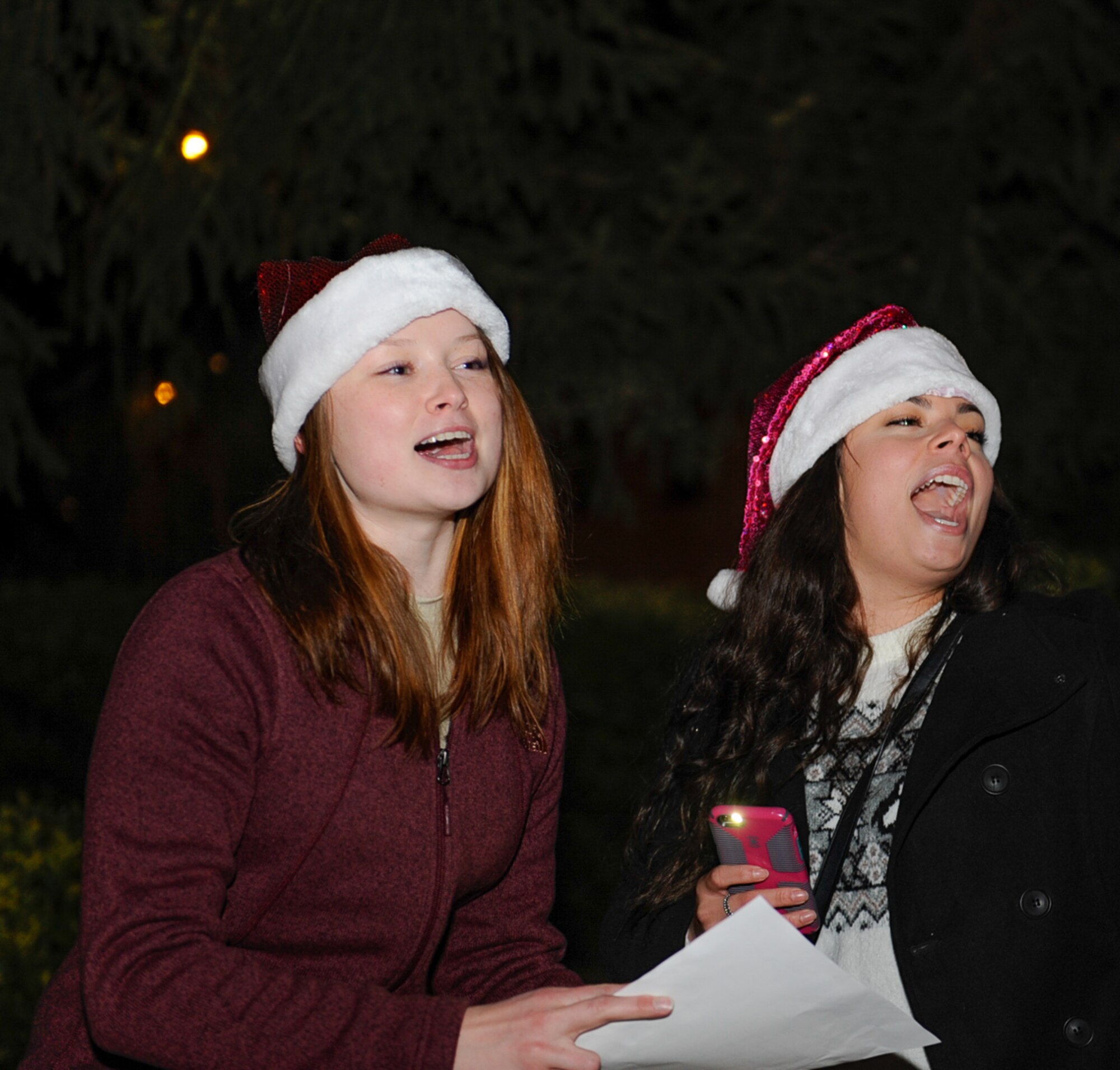 Airman 1st Class Morgan Lackey (left) and Senior Airman Sofia Figueroa, both 86th Dental Squadron dental technicians, sing during a caroling competition at the 86th MDG Christmas tree lighting ceremony at Ramstein Air Base, Germany, Dec. 1, 2016. The 86th DS was one of four medical squadrons that participated in the competition.(U.S. Air Force photo/Airman 1st Class Savannah L. Waters)