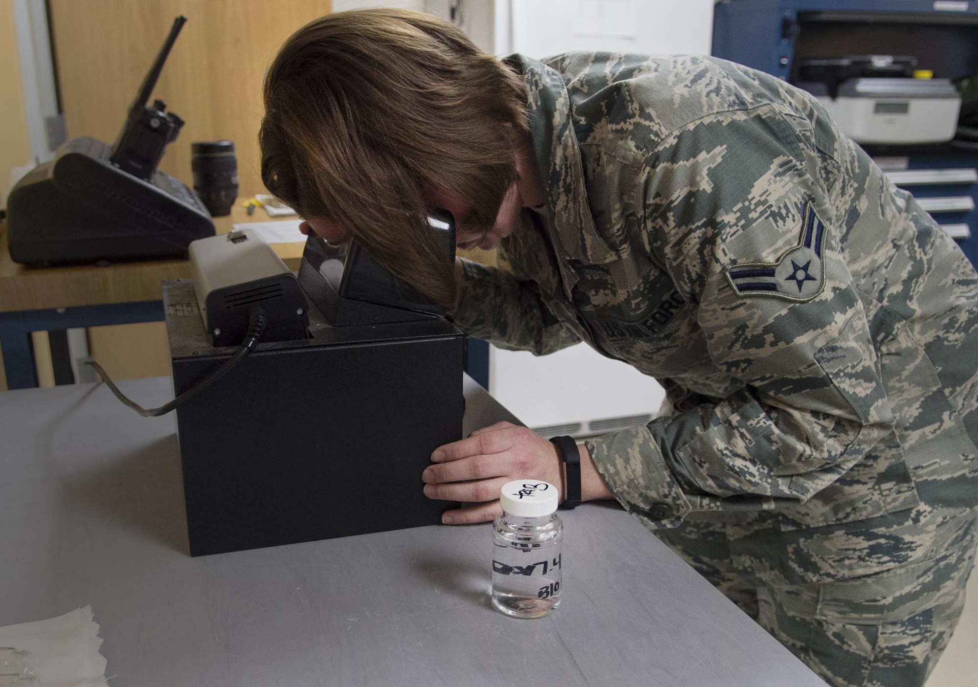 Airman 1st Class Sarah Vantilburg, 779th AMS bioenvironmental technician, checks a sample for bacteria using ultraviolet light during training on Joint Base Andrews, Md., Dec. 6, 2016. The test is incubated for 24 hours to promote growth of any bacteria and will glow luminescent under the ultraviolet light if bacteria is present. (U.S. Air Force photo by Senior Airman Mariah Haddenham)