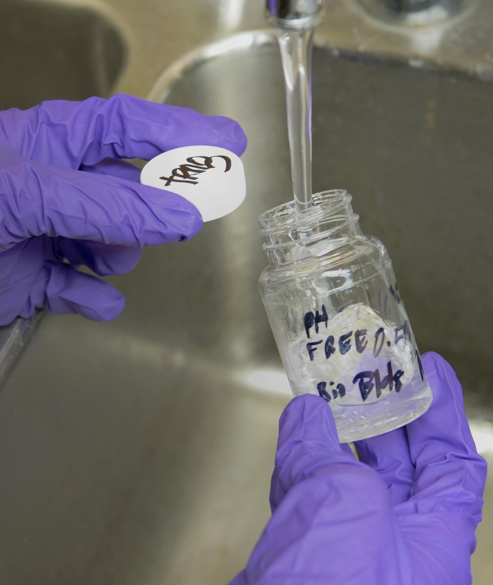 Airman 1st Class Brandon Lees, 779th Aerospace Medicine Squadron bioenvironmental technician, fills a sample bottle at Joint Base Andrews, Md., Dec. 6, 2016. The Airmen perform more than 140 water tests each year and also assess shops for occupational hazards to keep JBA members safe. (U.S. Air Force photo by Senior Airman Mariah Haddenham)