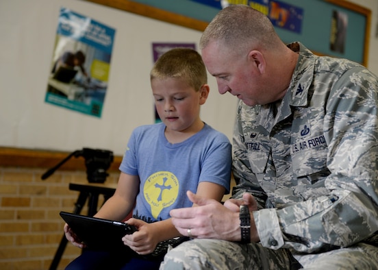 U.S. Air Force Col. Lance Whitfill, 97th Mission Support Group commander, looks on as a student controls a robot, December 6, 2016, Altus Air Force Base, Oklahoma. The STEM initiative hopes to inspire the next generation to take an interest in science, technology, engineering and mathematics. (U.S. Air Force Photo by Airman Jackson N. Haddon/Released).