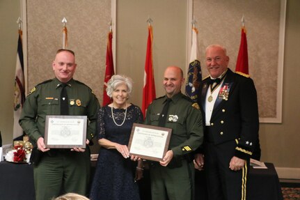 West Virginia State Police 1st Lt. J.L. “Red” Cooper and Sgt. Andy Evans are awarded certificates of appreciation from Maj. Gen. Leslie (Les) J. Carroll, commanding general of the 377th Theater Sustainment Comand, as Rainelle, W.Va., Mayor Andrea “Andy” Pendleton stands by, during the 321st Ordnance Battalion Dining Out in Daniels, W. Va., Dec. 3, 2016, for meritorious achievement and leadership in support of the disaster recovery operations in Rainelle, W.Va. during historic flooding of 24 through 27 June, 2016.