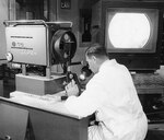 Lt. Col. Helmuth Sprinz, a surgical patholisgist at Walter Reed Army Medical Center, operates a color television microscope, designed by WRAMC and RCA technicians in 1957.