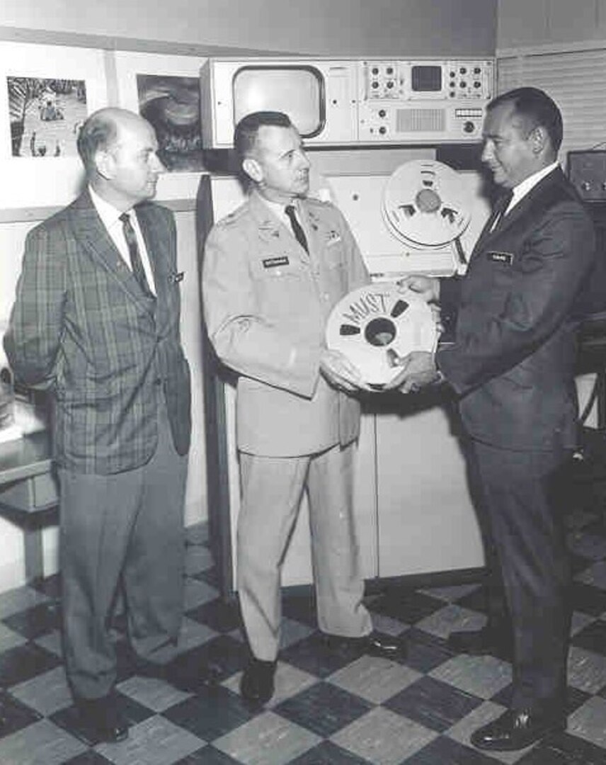 In 1967, one of MFSS-TV’s first productions, a one-hour program on the Medical Unit Self-Contained Transportable, or MUST, was produced alongside the Army Photographic Agency Unit over the course of six days for the cost of $1,500. At the time, a typical instructional motion picture of its length would have taken at least three months and an average of $75,000 to produce.  Lt. Col. Stephen P. Dittman (center), the first MFSS-TV chief, is holding the video reel.