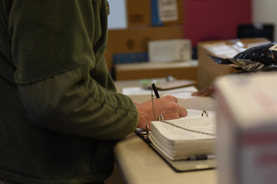 An Airman signs for a package at Barksdale Air Force Base, La., Dec. 7, 2016. The postal service center requires picture identification and signature from anyone retrieving a package to verify the owner has received their property. (U.S. Air Force photo/Airman 1st Class Alexis C. Schultz)