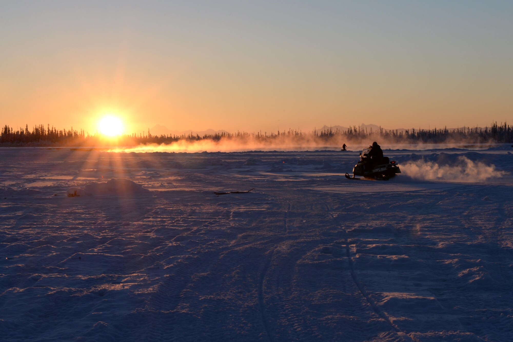 U.S. Air Force Airmen from the 354th Civil Engineer Squadron use snow machines to get across the ice bridge leading to the Blair Lakes Range Maintenance Complex Dec. 5, 2016, in Fairbanks, Alaska. The 354th CES Airmen build up the ice bridge across the Tanana River every two years to aid in the mission of the Airmen who maintain the maintenance range and equipment. (U.S. Air Force photo by Airman 1st Class Cassandra Whitman)