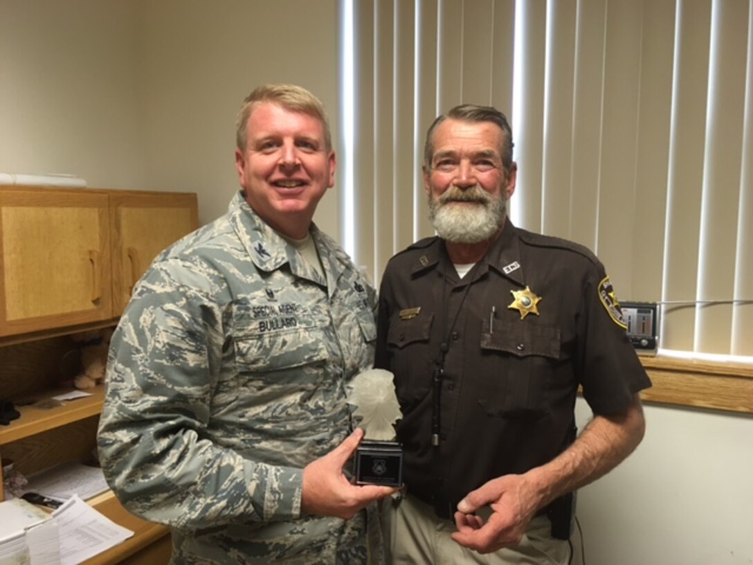 Col. Terry Bullard, Air Force Office of Special Investigations Region 2 Commander, presents Elmore County, Idaho, Sheriff Rick Layher a memento from AFOSI saluting his 40-year law enforcement career and long-standing working relationship with OSI Det. 221 at Mountain Home Air Force Base, Idaho. (U.S. Air Force photo/OSI Det. 221)    