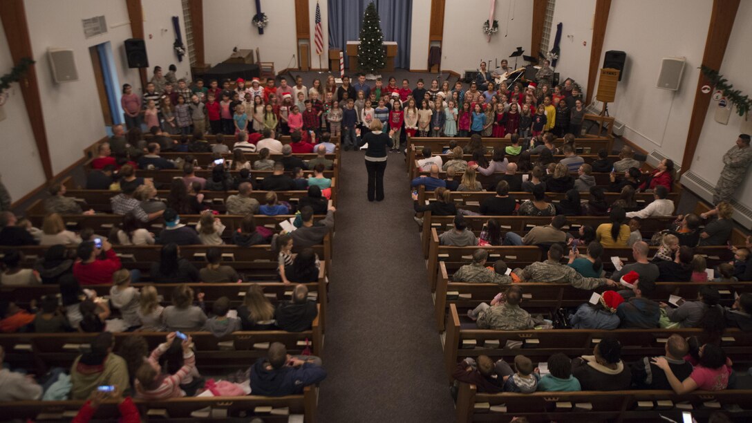 Team Dover Airmen and their families watch the Welch Elementary School chorus sing carols during the 2016 Dover Air Force Base Christmas Tree Lighting ceremony Dec. 6, 2016, at Chapel 2 on Dover AFB, Del. The event represents the kick off to the holiday season. (U.S. Air Force photo by Senior Airman Zachary Cacicia)