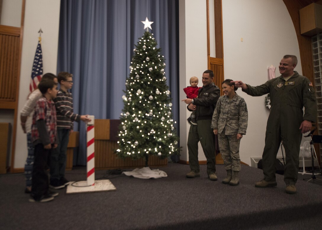 Col. Ethan Griffin, 436th Airlift Wing commander, Chief Master Sgt. Sarah Sparks, 436th AW command chief, Col. D. Scott Durham, 512th AW commander, and the family of Tech. Sgt. Jeremy Hase, 436th Maintenance Squadron, light the base Christmas Tree during the 2016 Christmas Tree Lighting ceremony Dec. 6, 2016, at Chapel 2 on Dover AFB, Del. Hase is currently deployed. (U.S. Air Force photo by Senior Airman Zachary Cacicia)