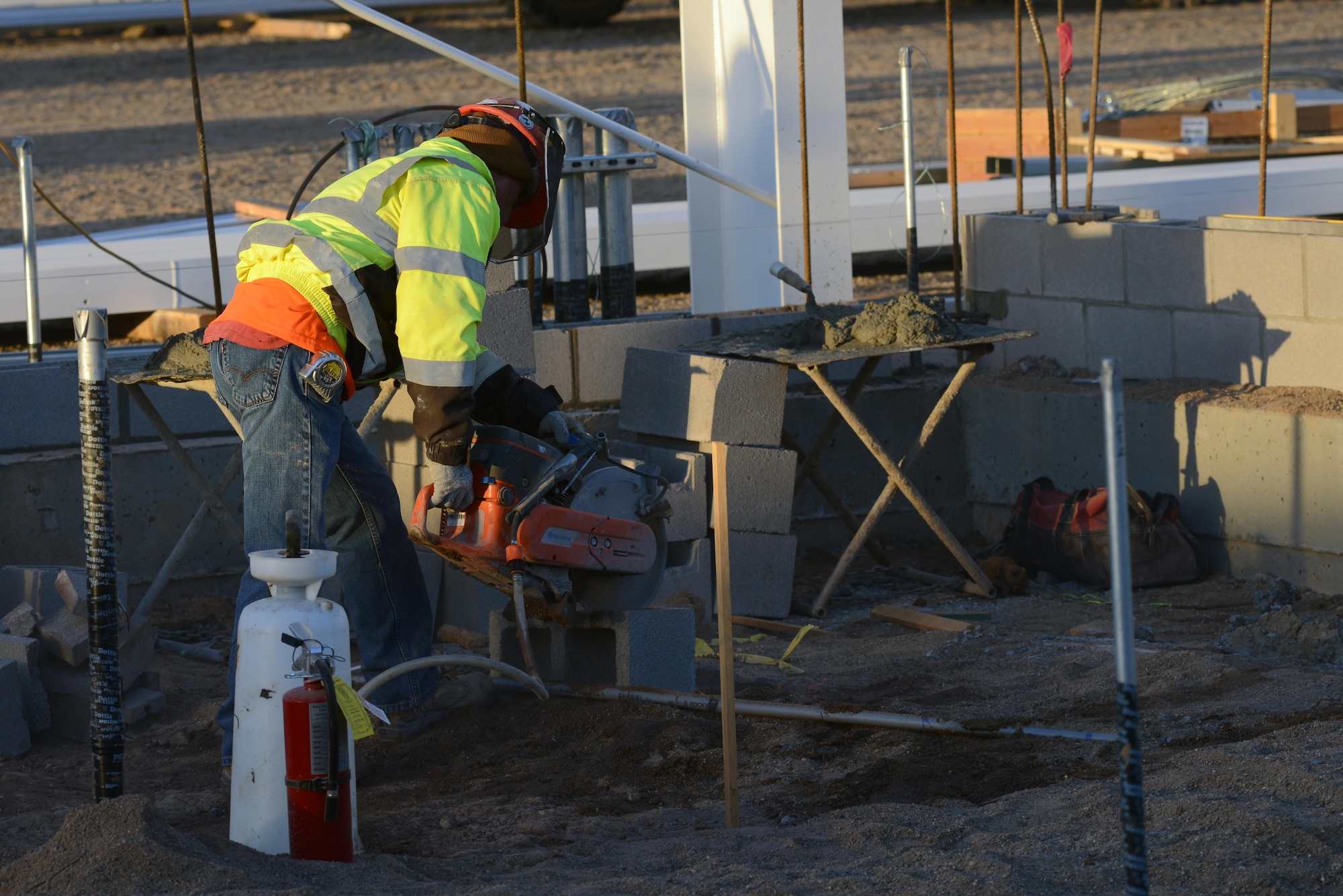 A 56th Civil Engineering Squadron general contractor cuts a concrete block for a wall corner piece Dec. 8, 2016, at Luke Air Force Base, Ariz. The building section of the hanger will contain a pad for the aircraft cooling unit and house an electrical room. (U.S. Air Force photo by Airman 1st Class Pedro Mota)