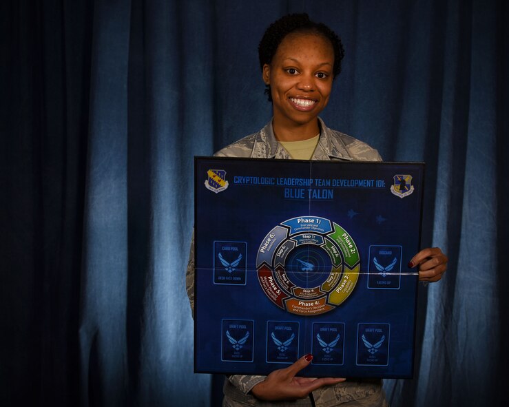 Staff Sgt. Monique McCoy, 70th Operations Support Squadron, wing mission training flight program manager, holds the board game portion of the Blue Talon training program. The mission training flight worked with a contractor to develop a program that could enable signals intelligence Airmen to gain an air operations mindset. (U.S. Air Force photo/Tech. Sgt. Veronica Pierce) 
