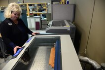 Sherry Pschernig, 341st Force Support Squadron’s Arts and Crafts Center engraver, creates a wooden plaque Dec. 7, 2016, at Malmstrom Air Force Base, Mont. The Engraving Shop has the capability to make wooden plaques from scratch by utilizing a machine that can burn personalized designs and words into the wood. (U.S. Air Force photo/Airman 1st Class Magen M. Reeves)	