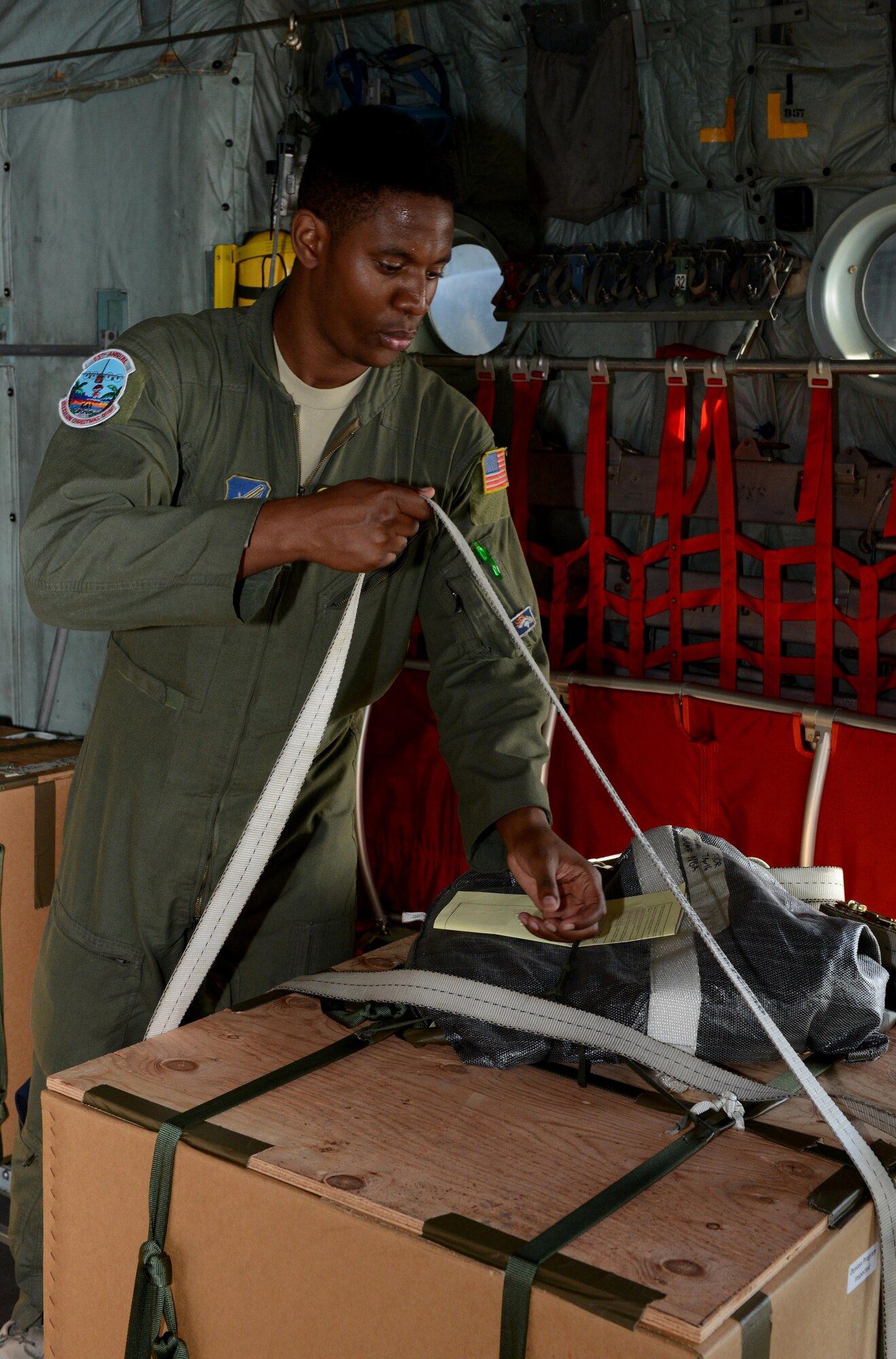 Senior Airman Deondre Rogers, a loadmaster from the 36th Airlift Squadron, Yokota Air Base, Japan, ties down bundles Dec. 7, 2016, at Andersen Air Force Base, Guam for Operation Christmas Drop. This operation has been in existence for   65 years. Operation Christmas brings food, clothes, toys and supplies to islanders throughout the Pacific via C130 Hercules airdrops. (U.S. Air Force photo by Senior Airman Arielle K. Vasquez/Released)