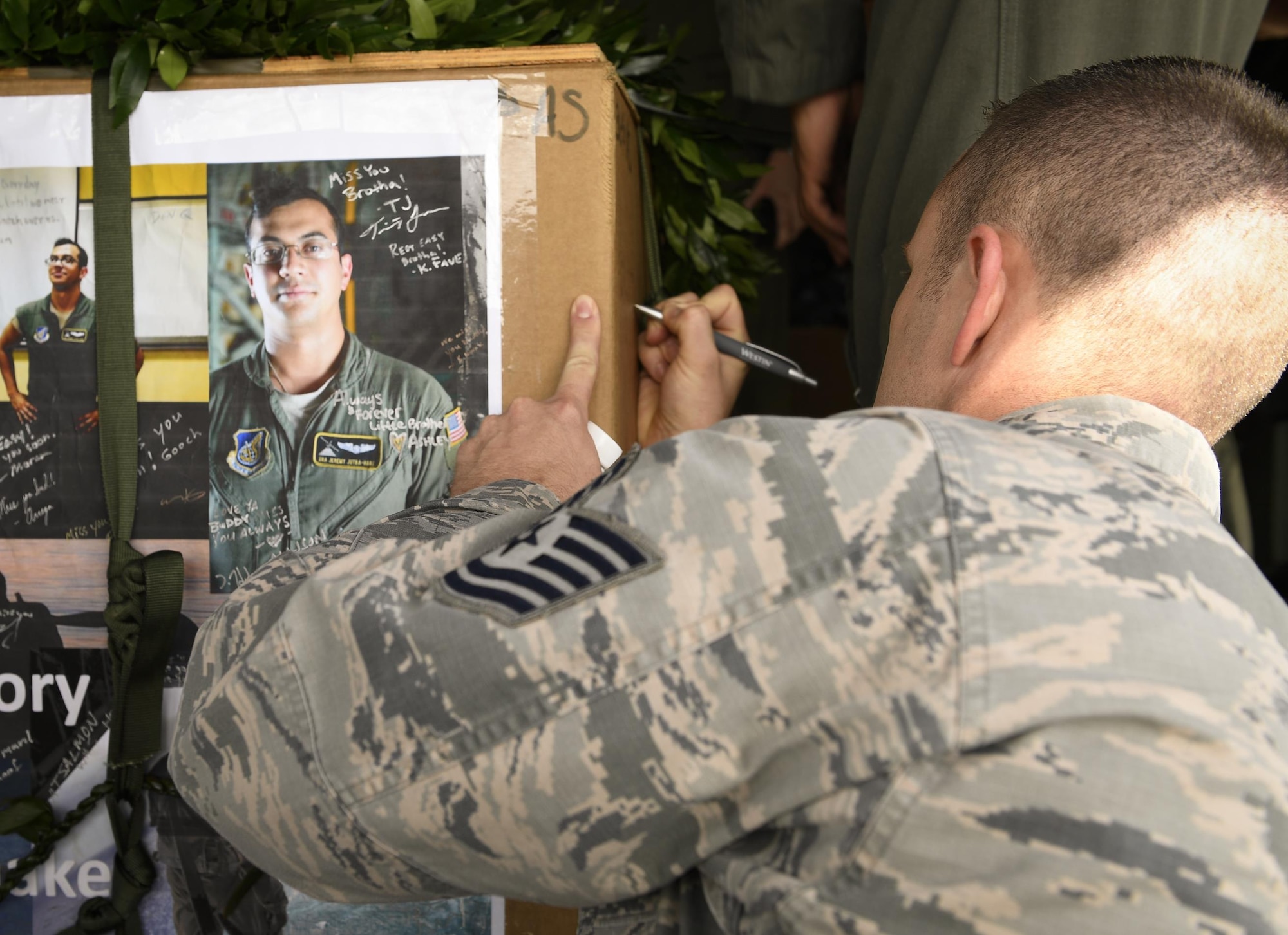 An Airman participating in Operation Christmas Drop signs the memorial aerial delivery bundle for Senior Airman Jeremy Jutba-Hake, 36th Airlift Squadron instructor loadmaster, at Andersen Air Force Base, Guam, Dec. 6, 2016. The 36 AS dropped Jutba-Hake’s memorial bundle, filled with donated supplies, on the Micronesian island of Satawal. After the drop, the island’s entire population of 600 stood on the beach to wave and thank the passing aircrew. (U.S. Air Force photo by Senior Airman Elizabeth Baker/Released)