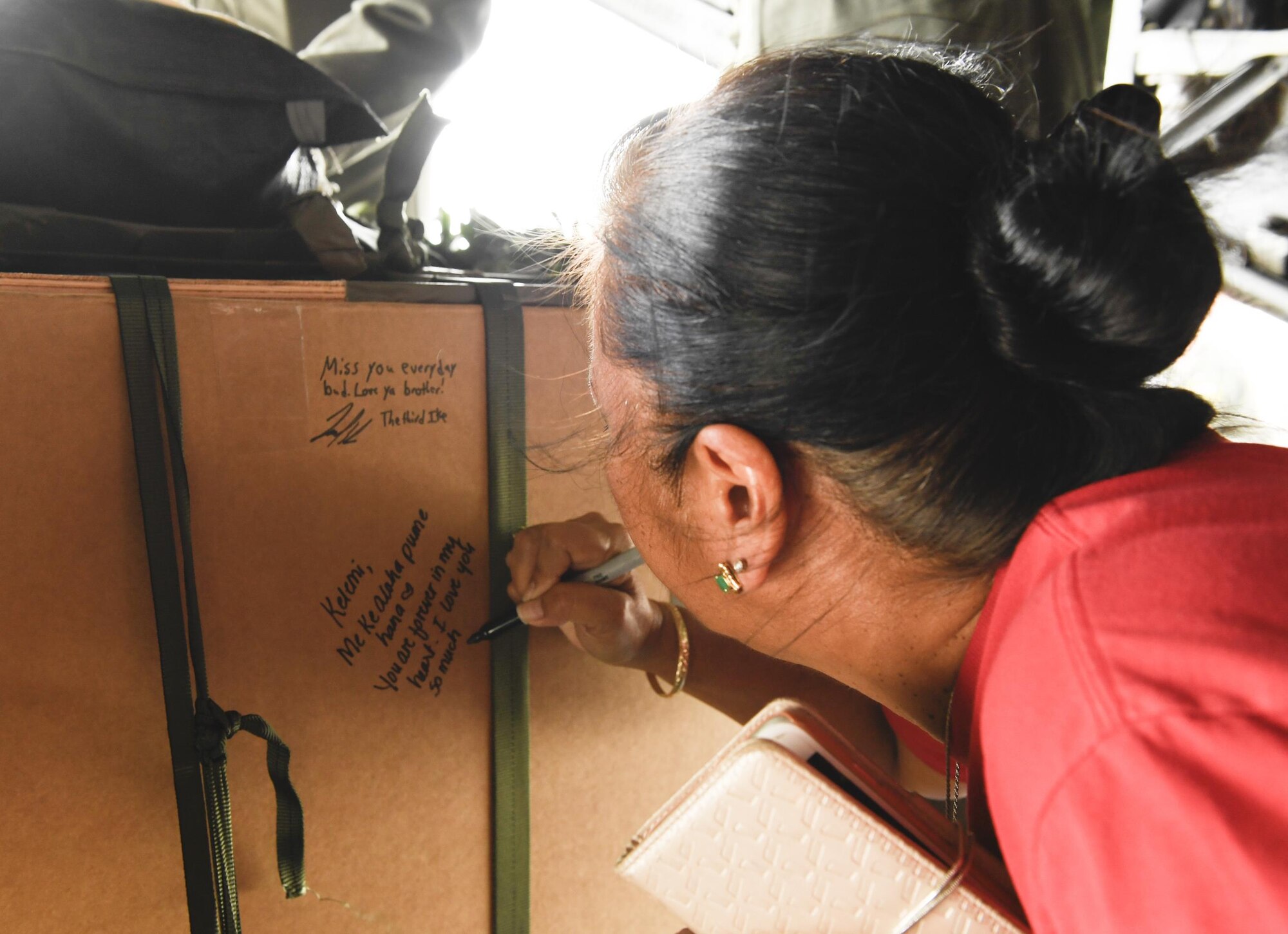 Eva Hake signs the memorial aerial delivery bundle for her late son, Senior Airman Jeremy Jutba-Hake, 36th Airlift Squadron instructor loadmaster, at Andersen Air Force Base, Guam, Dec. 6, 2016. The 36 AS dropped Jutba-Hake’s memorial bundle, filled with donated supplies, on the Micronesian island of Satawal as part of Operation Christmas Drop 2016. (U.S. Air Force photo by Senior Airman Elizabeth Baker/Released)