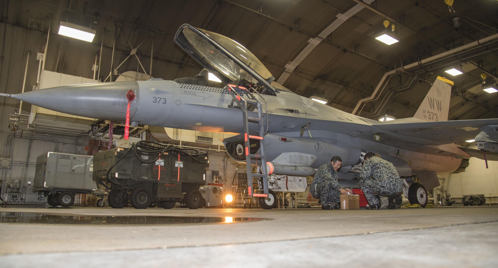 Japan Air Self-Defense Force Staff Sgts. Narihito Tanaka, left, and Kenta Okazaki, right, speak with U.S. Air Force Staff Sgt. Christopher Ransom, a 14th Aircraft Maintenance Unit F-16 Fighting Falcon avionics technician, during surge week at Misawa Air Base, Japan, Dec. 6, 2016. A surge is a time period where maintenance personnel experience increased operation tempo to simulate a deployed environment. (U.S. Air Force photo by Airman 1st Class Sadie Colbert)