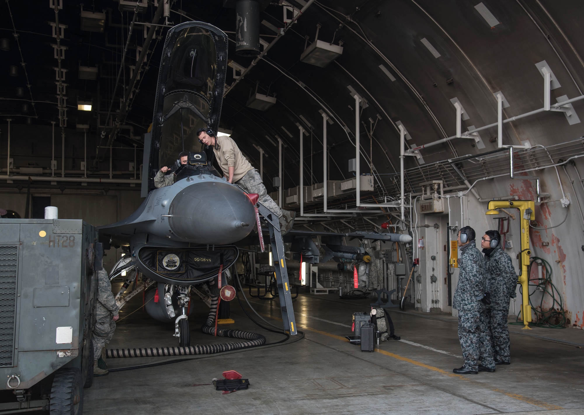 U.S. Air Forec Airman 1st Class Glenn Koontz, left, and Senior Airman Corey Robinson, center right, both 14th Aircraft Maintenance Unit electrical and environmental technicians, work on an F-16 Fighting Falcon as Japan Air Self-Defense Force Staff Sgts. Narihito Tanaka, center left, and Kenta Okazaki, right, sepctate aircraft procedures at Misawa Air Base, Japan, Dec. 7, 2016. Eight enlisted and two officers from multiple JASDF bases across Northern Japan participated in a bilateral exchange to learn maintenance procedures. (U.S. Air Force photo by Airman 1st Class Sadie Colbert)