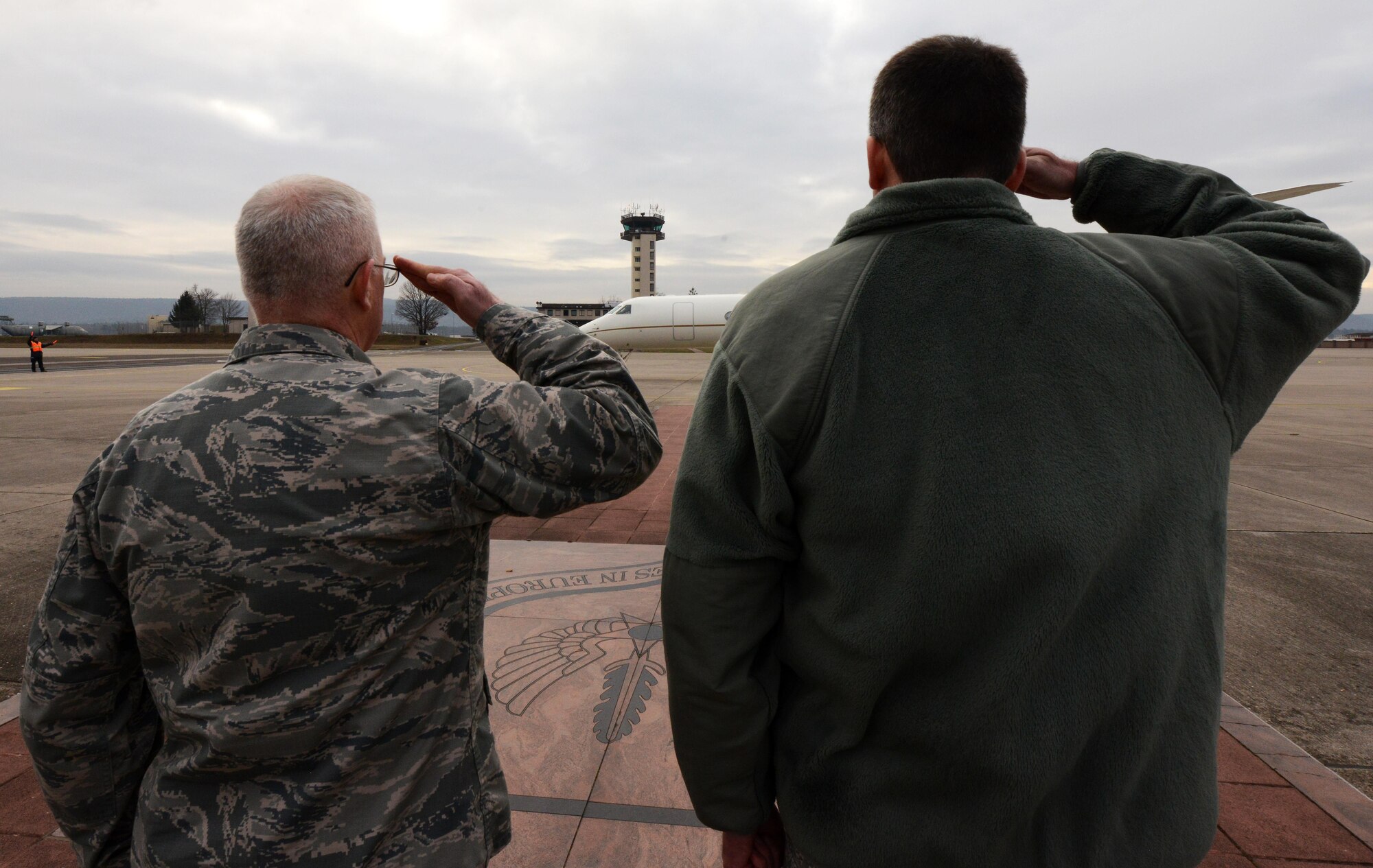 U.S. Air Force Col. Martin Giacobbi, 86th Dental Squadron commander (right), and U.S. Air Force Lt. Col. Harley Thompson, U.S. Air Forces in Europe and Air Forces Africa chief of legislative affairs (left), salute the departing plane of the Wisconsin, Oklahoma, and Nevada governors at Ramstein Air Base, Germany, Dec. 9, 2016. The governors traveled to the U.S. Air Forces Central Command area of responsibility to interact with their constituents. (U.S. Air Force photo by Senior Airman Jonathan Bass)