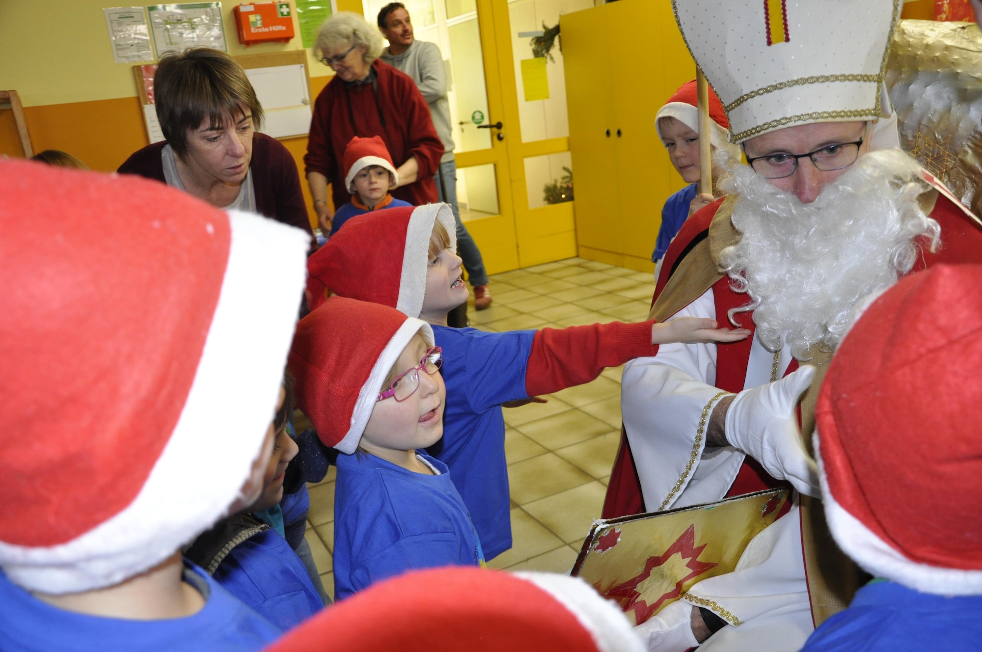 Saint Nicholas shakes hands and discusses the good things of the year with kindergarten children of the Bitburg Saint Martin school during the school’s annual Saint Nicholas celebration, Dec. 5 in Bitburg. The event included a visit by Saint Nicholas, dances and singing performances by the children, as well as a gift presentation by the 52nd Fighter Wing. The celebration was attended by Saint Martin school officials, parents, 52nd Fighter Wing leadership spouses, as well as Airmen and civilians from the wing, who provided gifts to students and kindergarten children. In the summer,  Spangdahlem Sabers invited the Saint Martin school to Special Children’s Day at Spangdahlem AB, where they played games and spent a fun-filled time together. (U.S. Air Force photo by Iris Reiff)