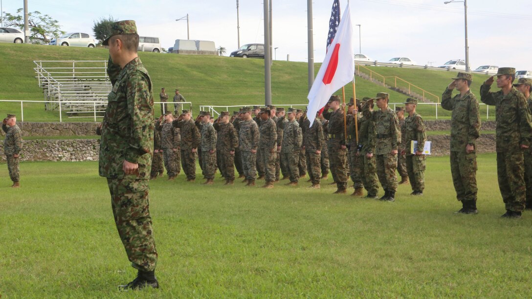 U.S. Marines with 3d Marine Expeditionary Brigade and service members of the Japan Ground Self-Defense Force salute the national colors of both nations at Camp Courtney, Okinawa, Japan, during the opening ceremony for Yama Sakura 71, Dec. 7, 2016,. The purpose of YS 71 is to enhance both nations’ combat readiness and interoperability while strengthening bilateral relationships and demonstrating U.S. resolve to support security interests of allies and partners in the Indo-Asia-Pacific region.