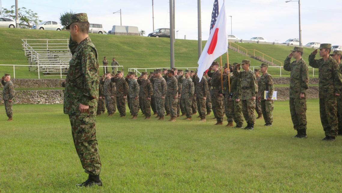 U.S. Marines with 3d Marine Expeditionary Brigade and service members of the Japan Ground Self-Defense Force salute the national colors of both nations at Camp Courtney, Okinawa, Japan, during the opening ceremony for Yama Sakura 71, Dec. 7, 2016,. The purpose of YS 71 is to enhance both nations’ combat readiness and interoperability while strengthening bilateral relationships and demonstrating U.S. resolve to support security interests of allies and partners in the Indo-Asia-Pacific region.