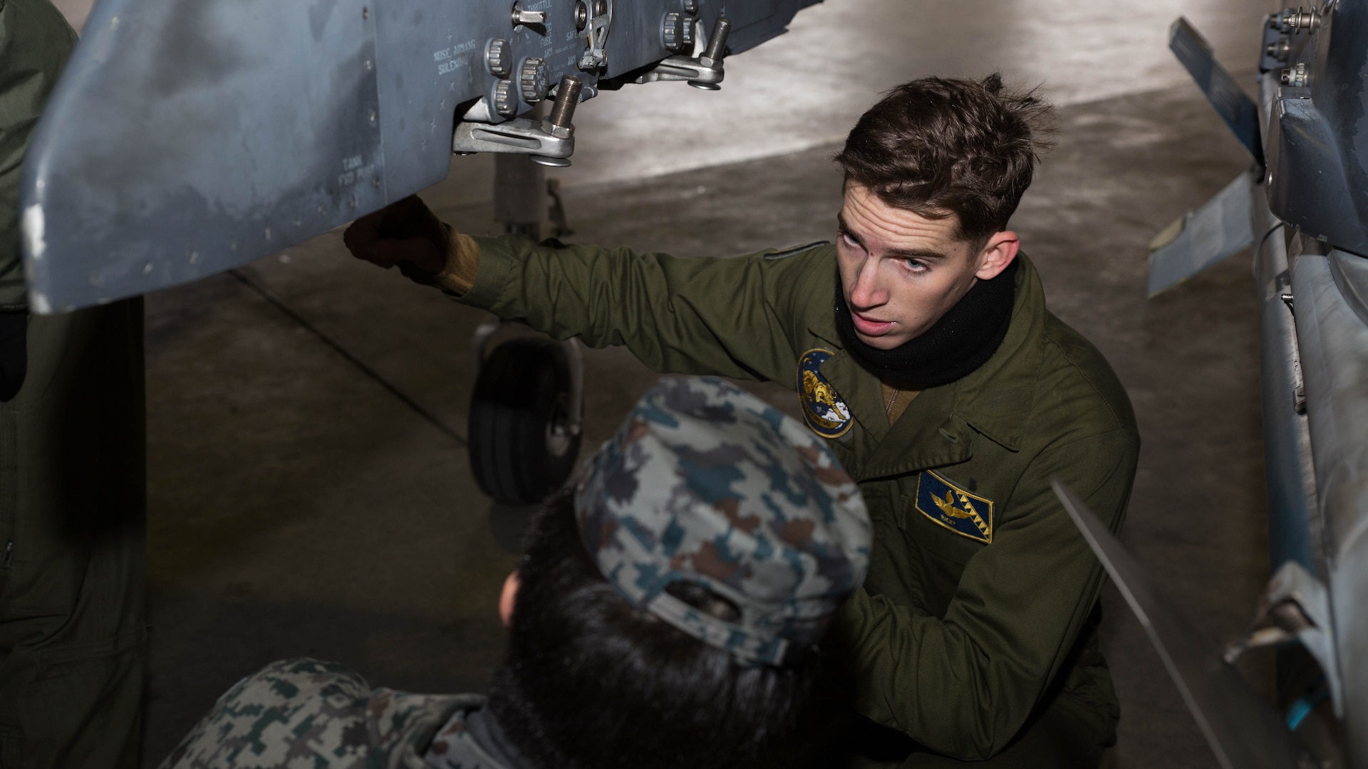 U.S. Marine Corps Cpl. Eli Gilbert, an ordnance technician with Marine Attack Squadron (VMA) 542, explains how parts of an AV-8B Harrier work to a member of the Japan Air Self Defense Force at Chitose Air Base, Japan, Dec. 9, 2016. JASDF personnel joined the VMA-542 Marines in their hangar to get a closer look and better understanding of the squadrons Harriers. (U.S. Marine Corps photo by Lance Cpl. Joseph Abrego)