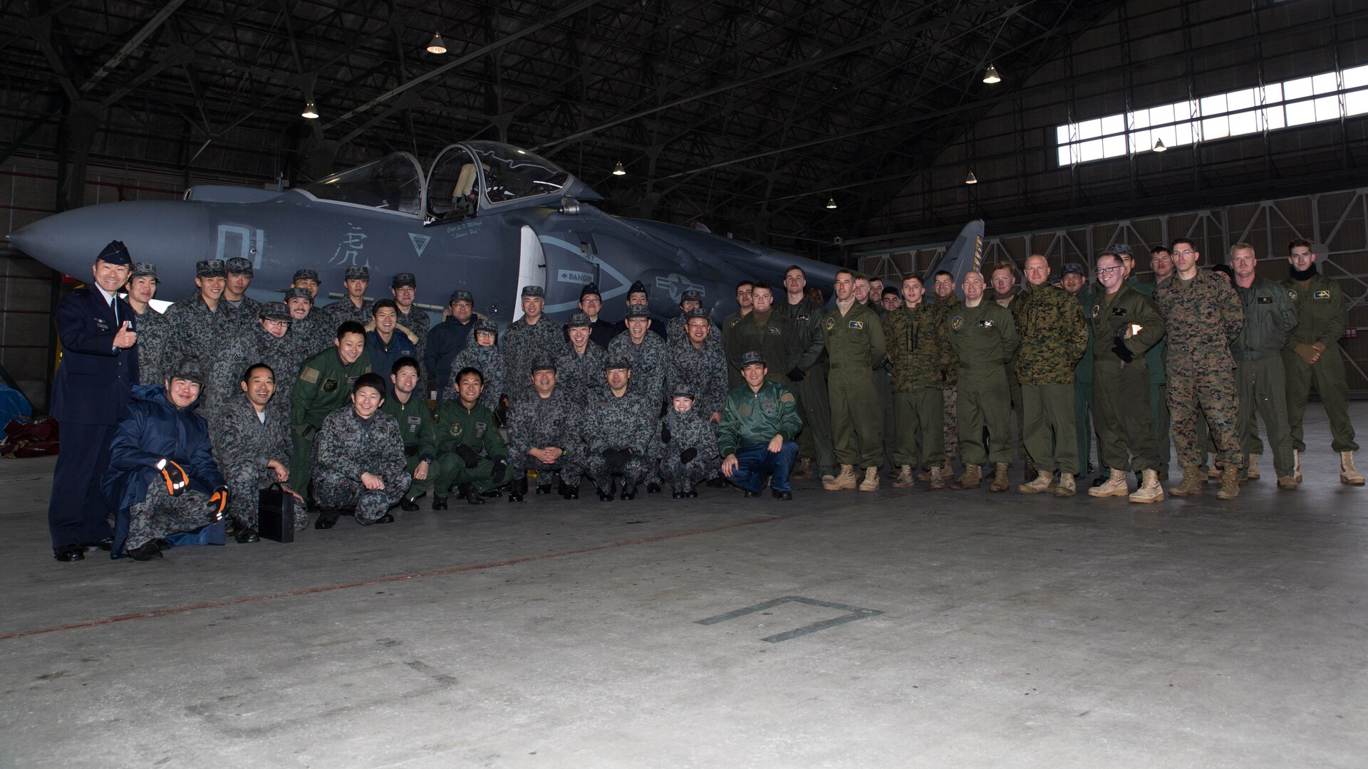 U.S. Marines with Marine Attack Squadron (VMA) 542 and Japan Air Self Defense Force personnel pose for a photo during the Aviation Training Relocation Program at Chitose Air Base, Japan, Dec. 9, 2016. JASDF personnel joined the VMA-542 Marines in their hangar to get a closer look and better understanding of the squadrons Harriers. (U.S. Marine Corps photo by Lance Cpl. Joseph Abrego)