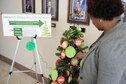 Daisy Jones-Brown, 14th Flying Training Wing Green Dot Coordinator, sets up an interactive Christmas tree representing the Green Dot program Dec. 2, 2016, in the Wing Headquarters building at Columbus Air Force Base, Mississippi. Members can read a red dot and choose a green dot to set over it based on how the member would either direct, delegate, or distract in that red dot situation. (U.S. Air Force photo by Senior Airman Kaleb Snay)