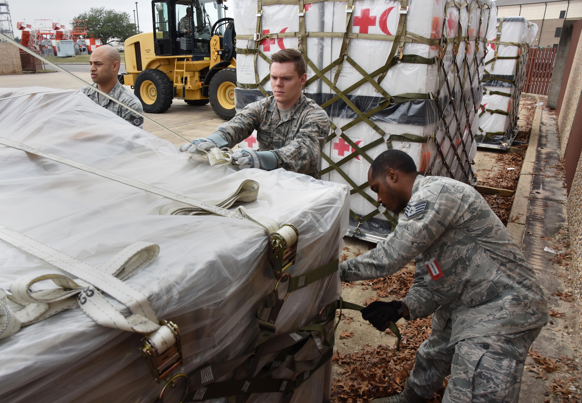Medical logistics technicians from the 81st Medical Support Squadron logistics technicians tighten cargo straps at the supply warehouse loading docks during a deployment exercise Dec. 7, 2016, on Keesler Air Force Base, Miss. The exercise scenario tested the mission readiness of Team Keesler for simultaneous world-wide deployments. (U.S. Air Force photo by Kemberly Groue)
