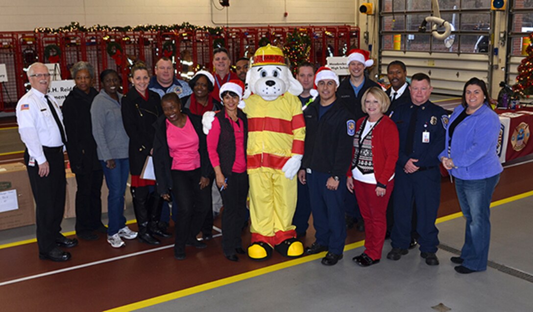 Sparky, the fire dog, poses in the fire station with Defense Logistics Agency Installation Support at Richmond’s Fire and EMS personnel and DSCR volunteers during Angel Tree gift drop off Dec. 8, 2016.  Employees adopted 113 angels from Chesterfield County and Richmond City Public Schools. 