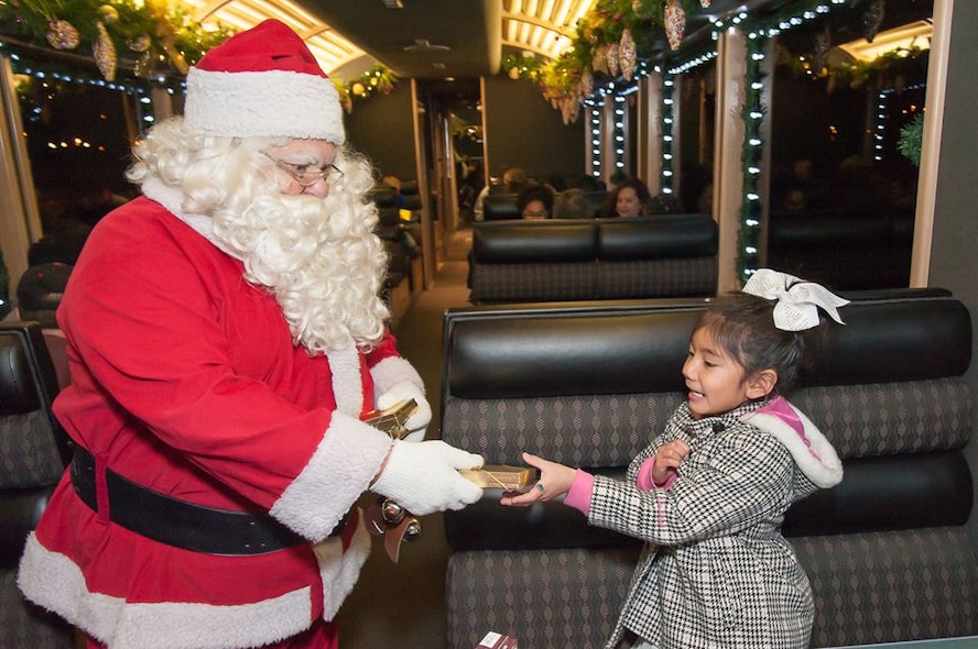 Santa Claus gives a young passenger aboard the Holiday Express a small gift. Burlington Northern and Santa Fe Railway Company, a nationwide freight transportation company, has been running its Holiday Express for the past eight years to give members of the military and their families the experience of riding a train. About 300 people experienced the holiday train ride. 