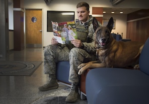 Staff Sgt. Derek Scrivener, 11th Security Forces Squadron military working dog handler, sits for a photo while waiting to complete a practice sweep with MWD Lenox the passenger terminal on Joint Base Andrews, Md., Dec. 8, 2016.  MWD’s work as force multipliers, using their senses in low-visibility situations to acknowledge things a handler might not see. (U.S. Air Force photo illustration by Senior Airman Mariah Haddenham)