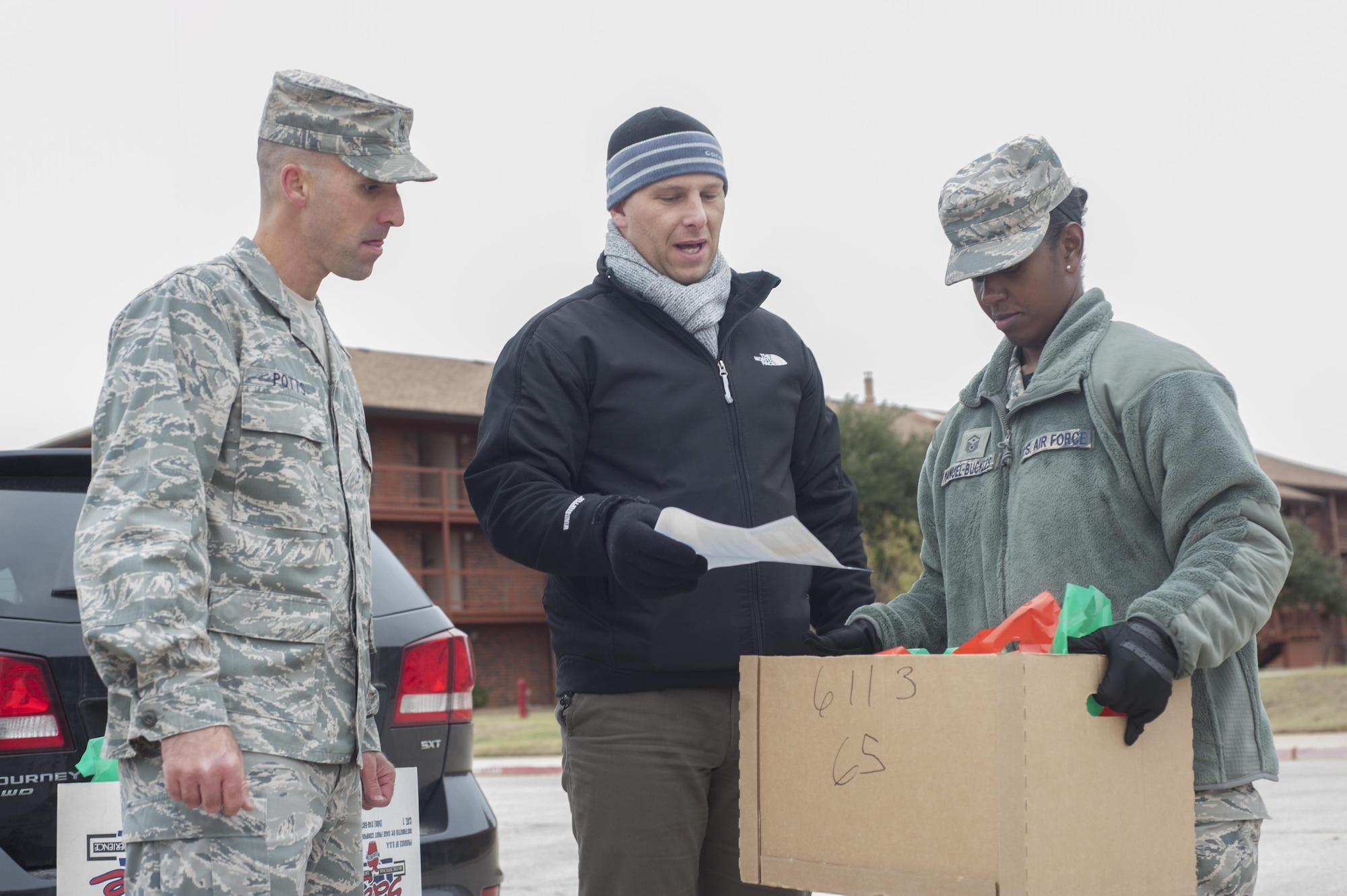 U.S. Air Force 1st Lt. Chadwick Potts, left, 7th Bomb Wing chaplain,  Master Sgt. Eric Siemsen, middle, 317th Operation Support Squadron first sergeant, and Master Sgt. Kimberly Manuel-Buckles, right, 7th Munitions Squadron first sergeant, look over a dorm resident list at Dyess Air Force Base, Texas, Dec. 9, 2016. As part of ensuring a successful mission for Operation Cookie Drop, Dyess first sergeants and other volunteers organized lists of occupied rooms in each dorm building so that every dorm resident receives a bag of cookies. (U.S. Air Force photo by Airman 1st Class Rebecca Van Syoc)