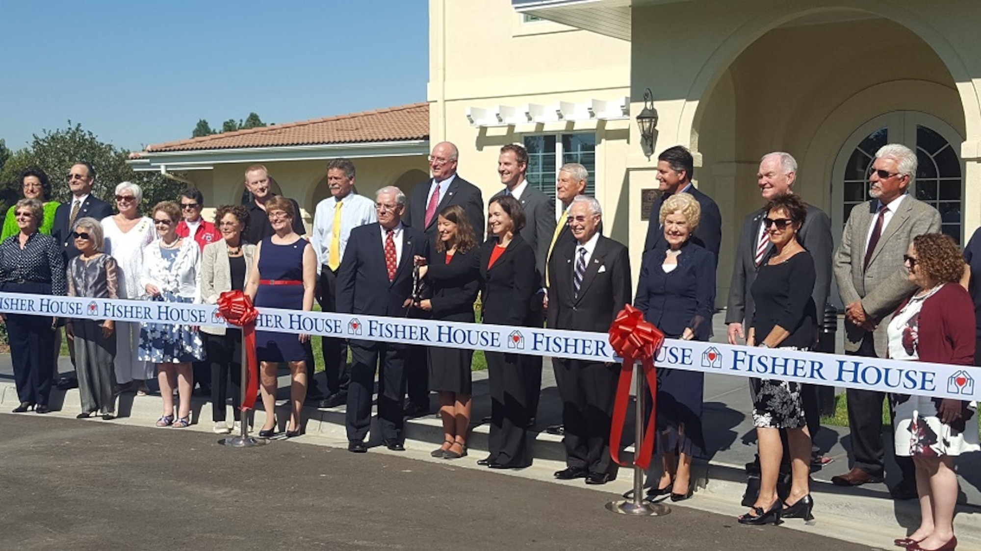 Tracye Davis, acting director of the Veterans Affairs Long Beach Healthcare System, holding scissors, and Fisher House Foundation president David Coker, left of Davis, with community supporters get ready to cut the ceremonial ribbon signifying the sixth and newest Fisher House to open in California during a dedication ceremony Oct. 19 at the VA Long Beach Medical Center. (Courtesy photo/ Fisher House Foundation)