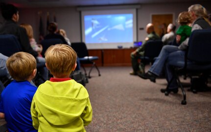 Two Storm Troopers, children who had parents on ride-out teams during Hurricane Matthew, watch a video highlighting the ride-out team members during a Storm Troopers ceremony at the Airman and Family Readiness Center here, Dec. 8, 2016. Nearly 23,000 base employees and their families evacuated Charleston Oct. 5, leaving a ride-out team of approximately 400 members to continue the base’s mission.